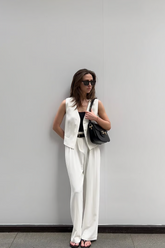 a lady wears a white suit vest with white suit pants